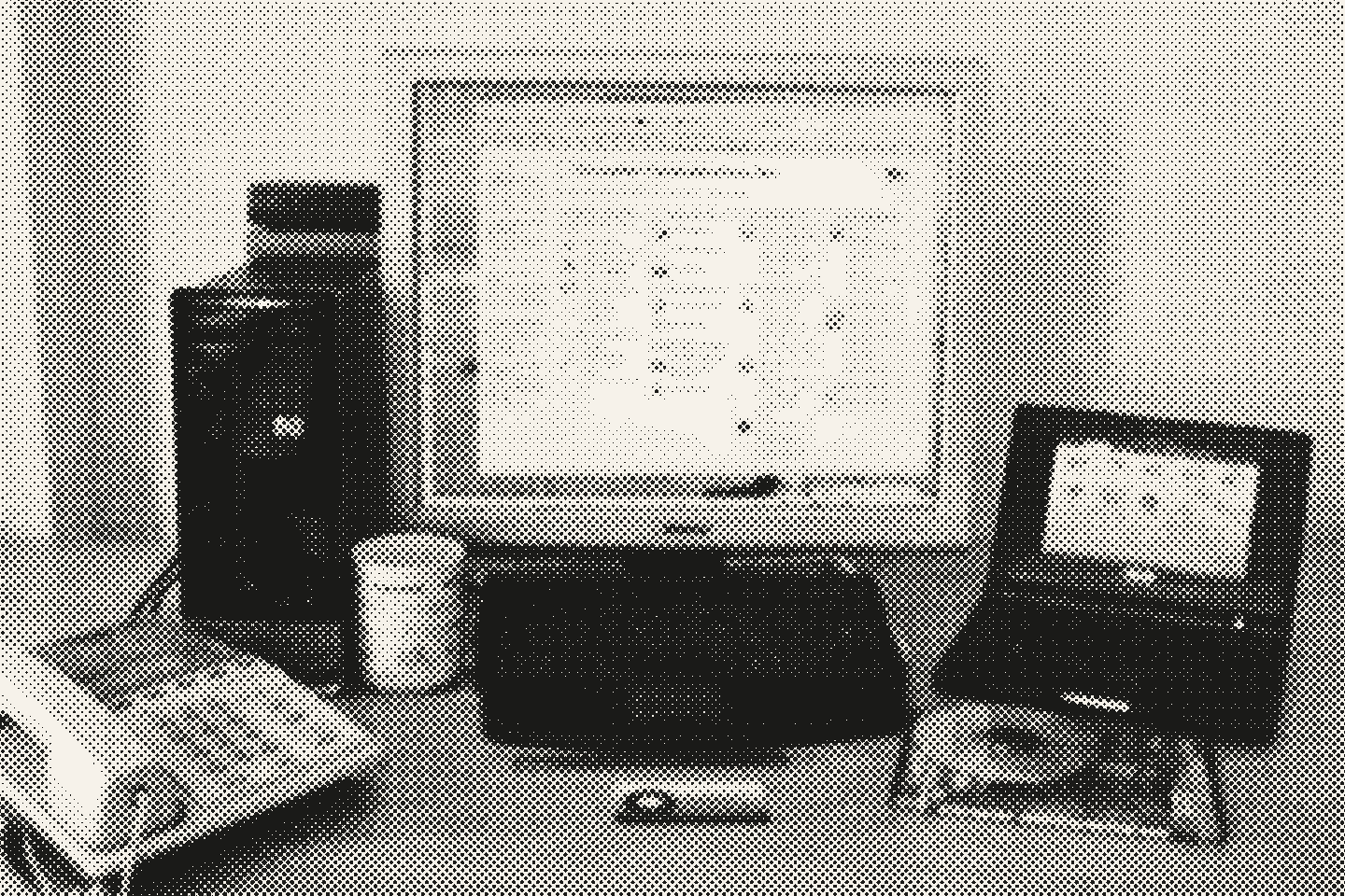 Escritorio con una torre, un monitor, un notebook pequeño y un teléfono fijo.